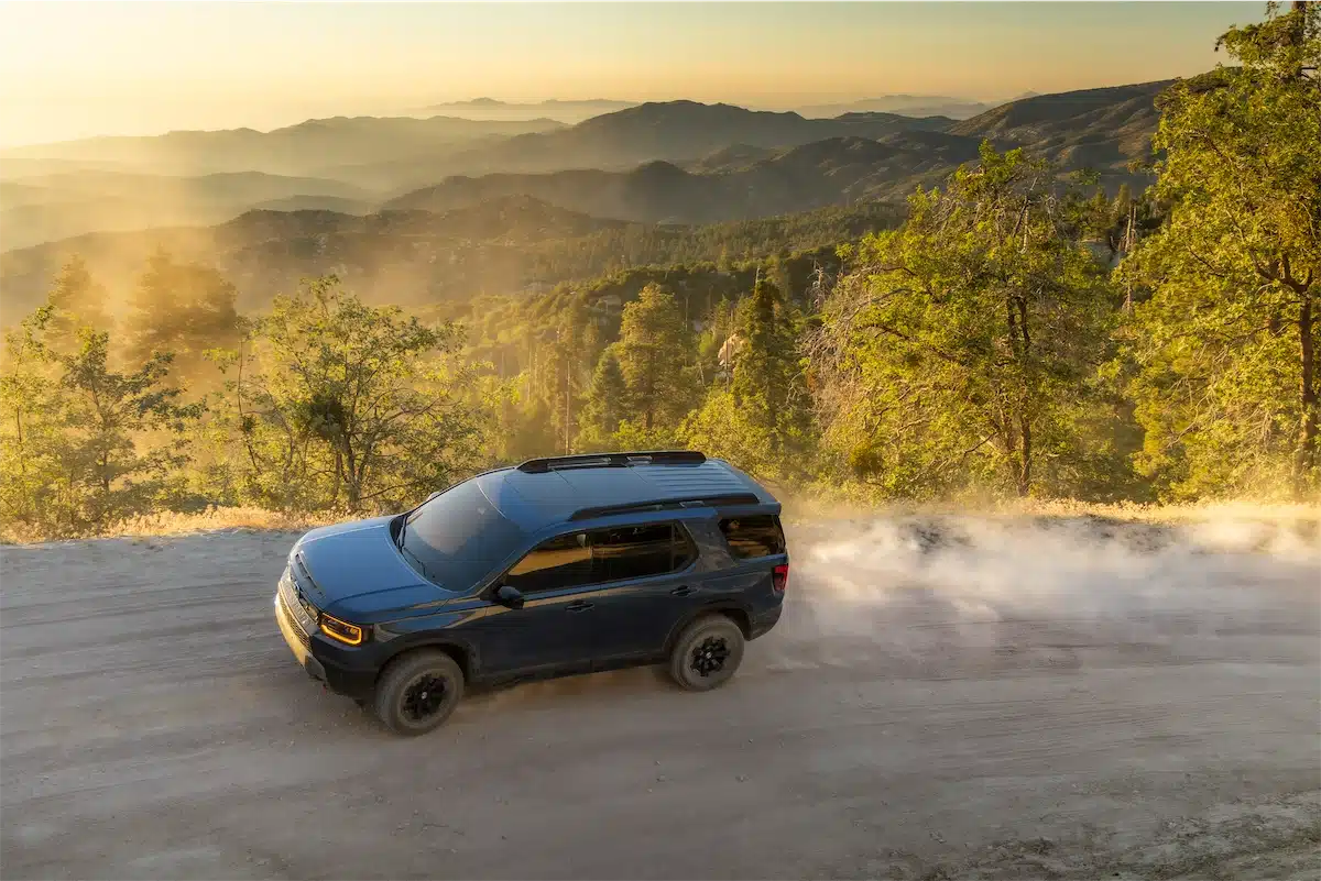 2027 Honda Passport TrailSport driving a mountain ridge trail at sunset