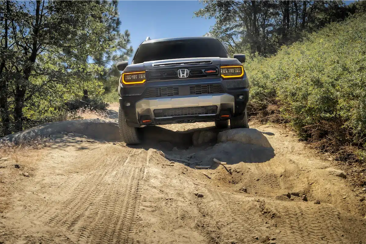 Front view of the 2027 Honda Passport TrailSport crawling over a trail obstacle