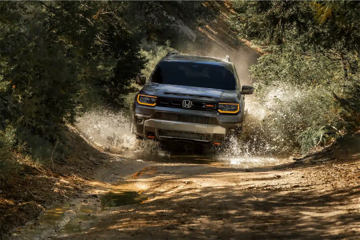 2027 Honda Passport TrailSport splashing through water on a forested trail