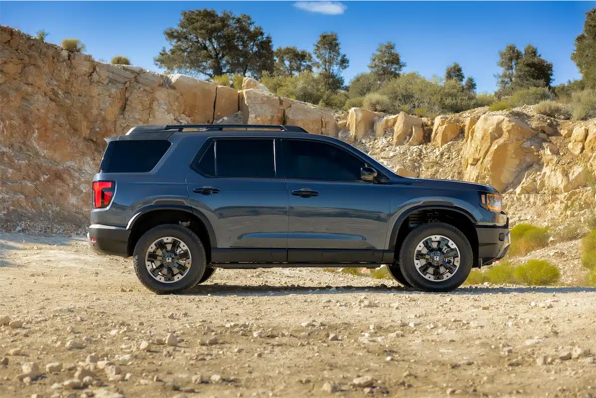 Side profile of the 2027 Honda Passport TrailSport parked beside a rock cliff