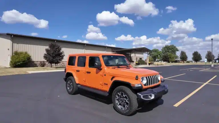 Orange 2025 Jeep Wrangler Sahara four-door in a parking lot