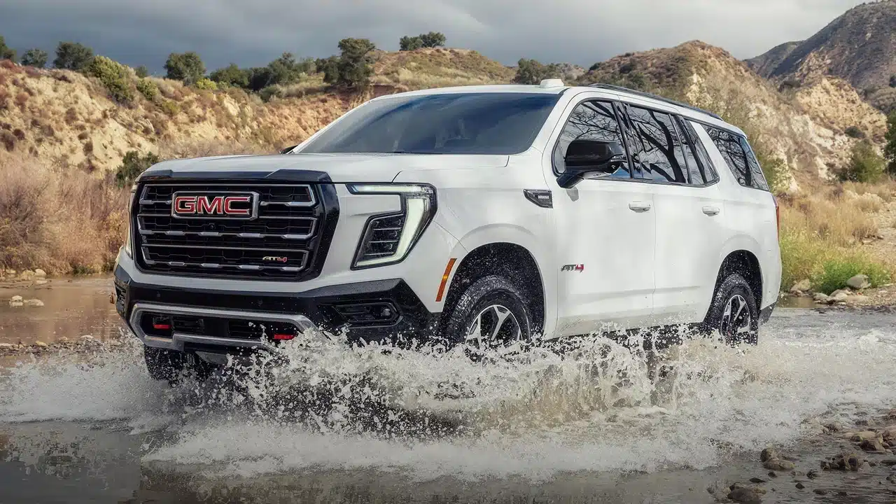 White GMC Yukon AT4 driving through shallow water