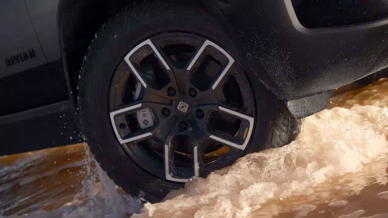 Rivian wheel and tire moving through shallow water