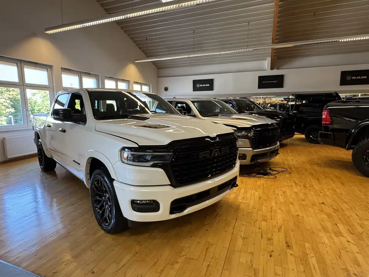 White Ram pickup at the front of a row of showroom trucks.
