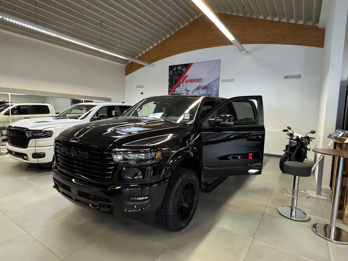 Black Ram pickup with its driver door open in the showroom.