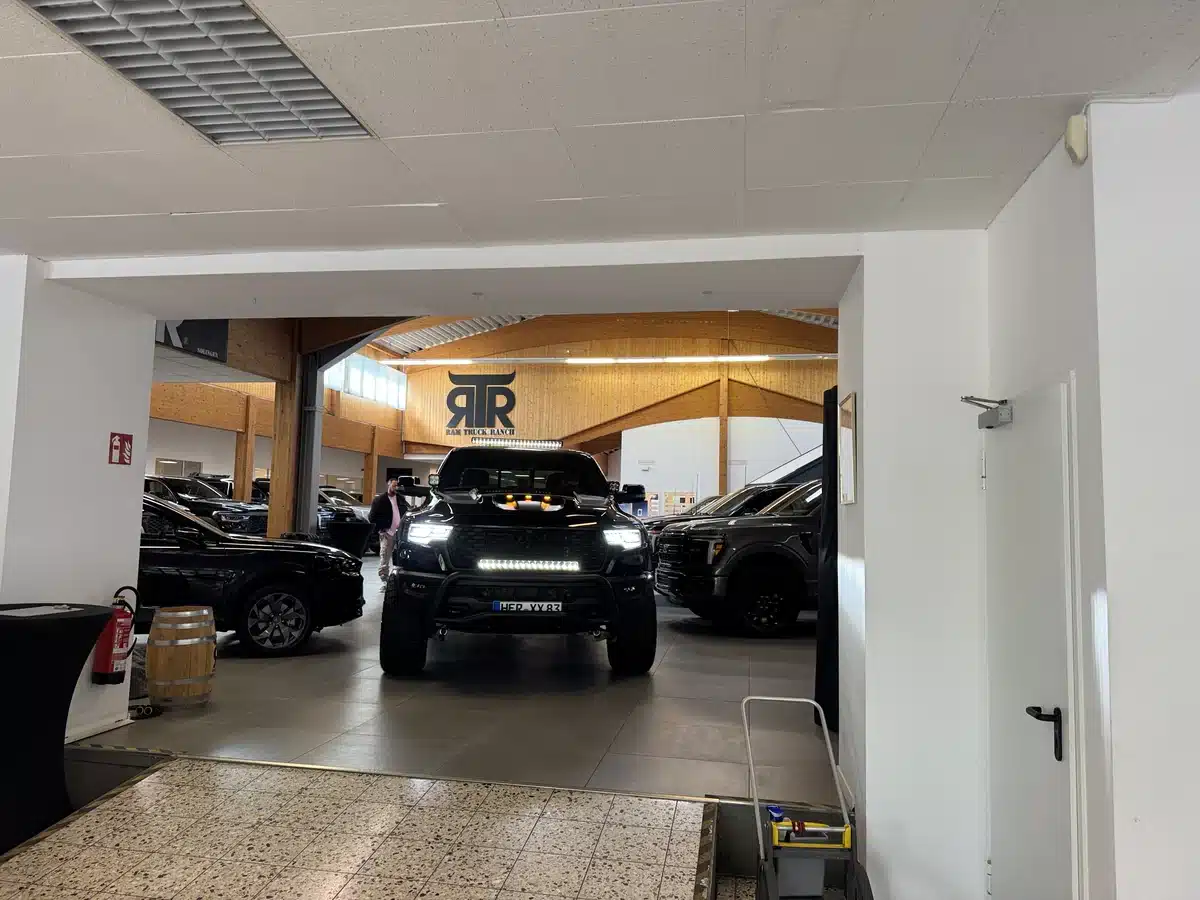 View through a narrow showroom passage toward a Ram pickup.