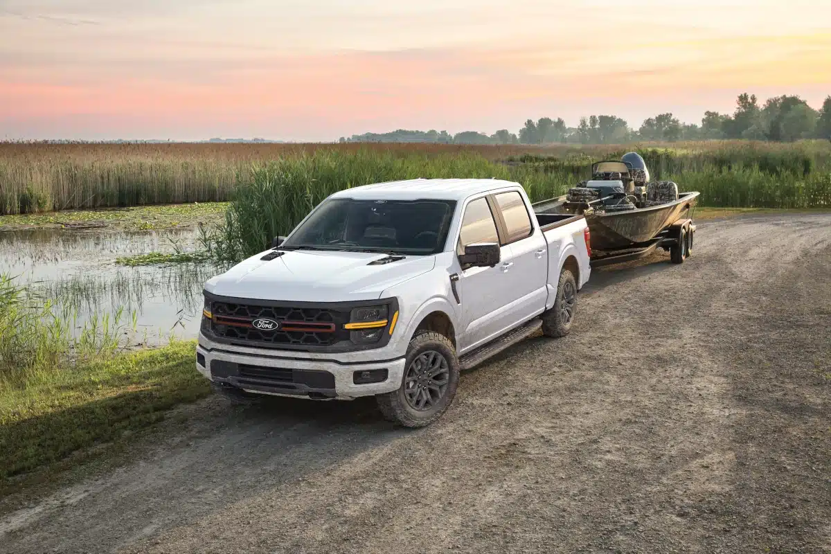 A white Ford F-150 towing a boat on a trailer.