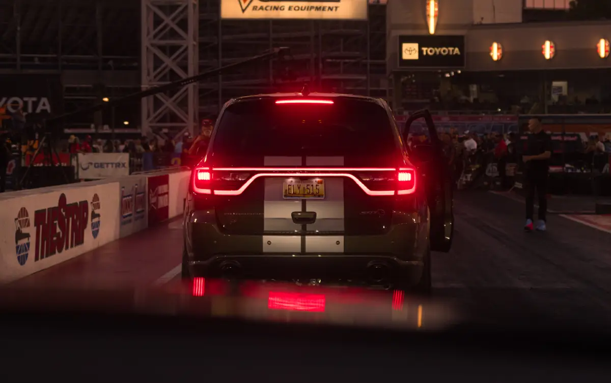 Rear of a Dodge Durango with its taillights illuminated at a drag strip