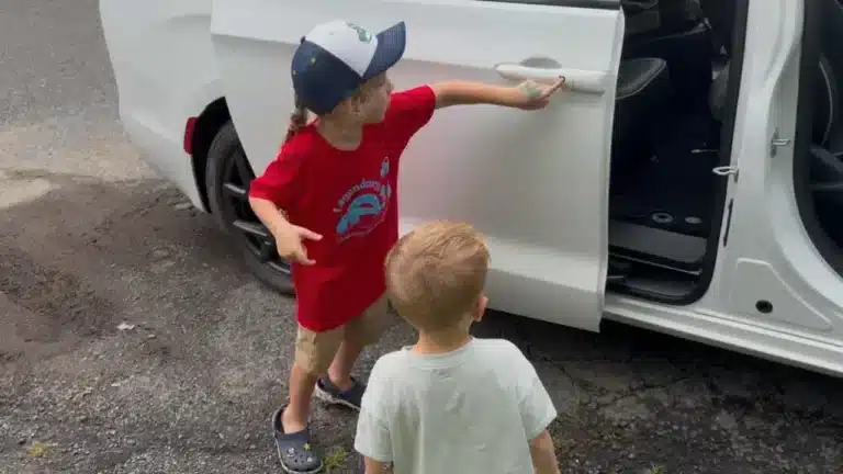 Lincoln and Leo beside the open sliding door of a 2027 Chrysler Pacifica