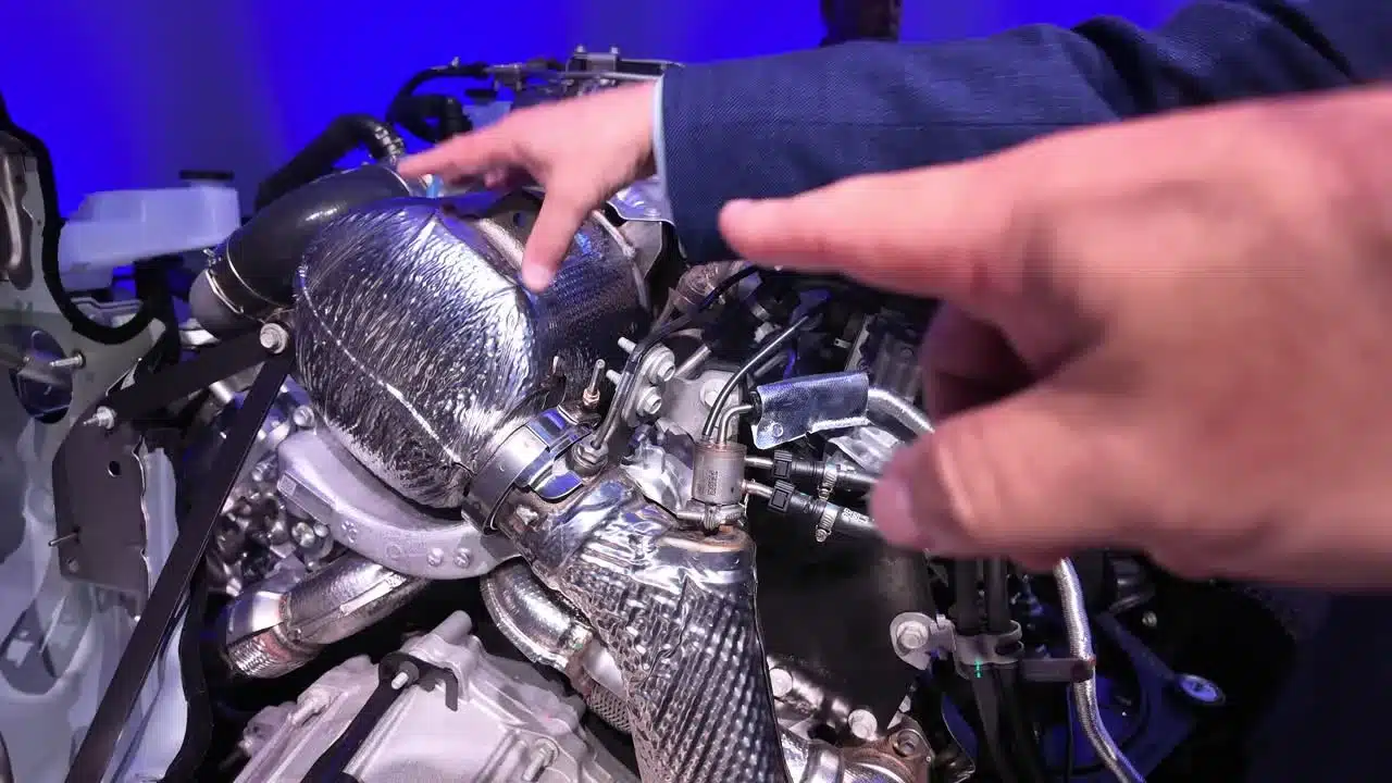 The engineer points out emissions hardware during the 8.3L Duramax walk-around.