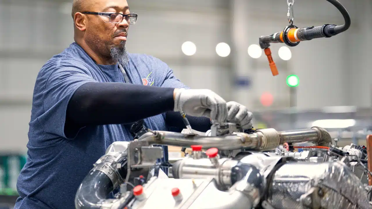 Worker inspecting an 8.3L Duramax at the DMAX factory