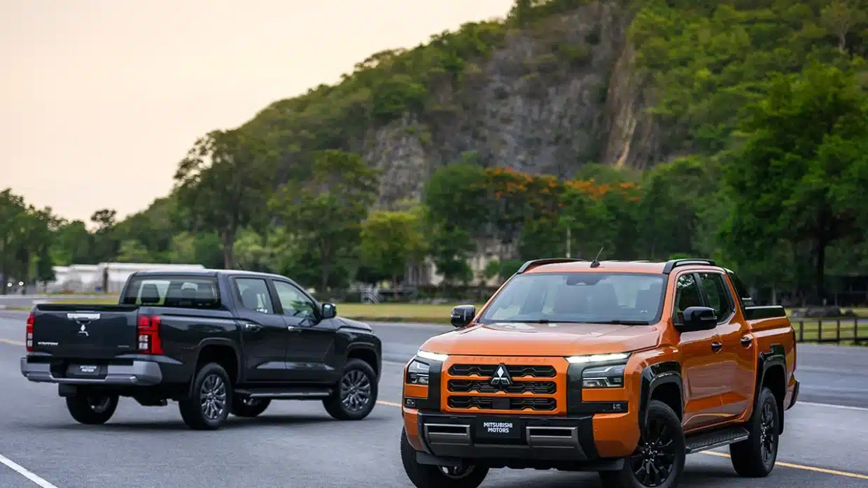 Two Mitsubishi Triton pickups, orange front view and black rear view